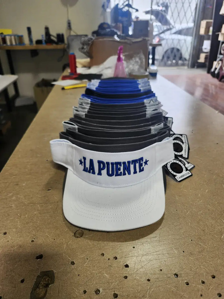 Stack of La Puente embroidered visors produced by DARTMAR